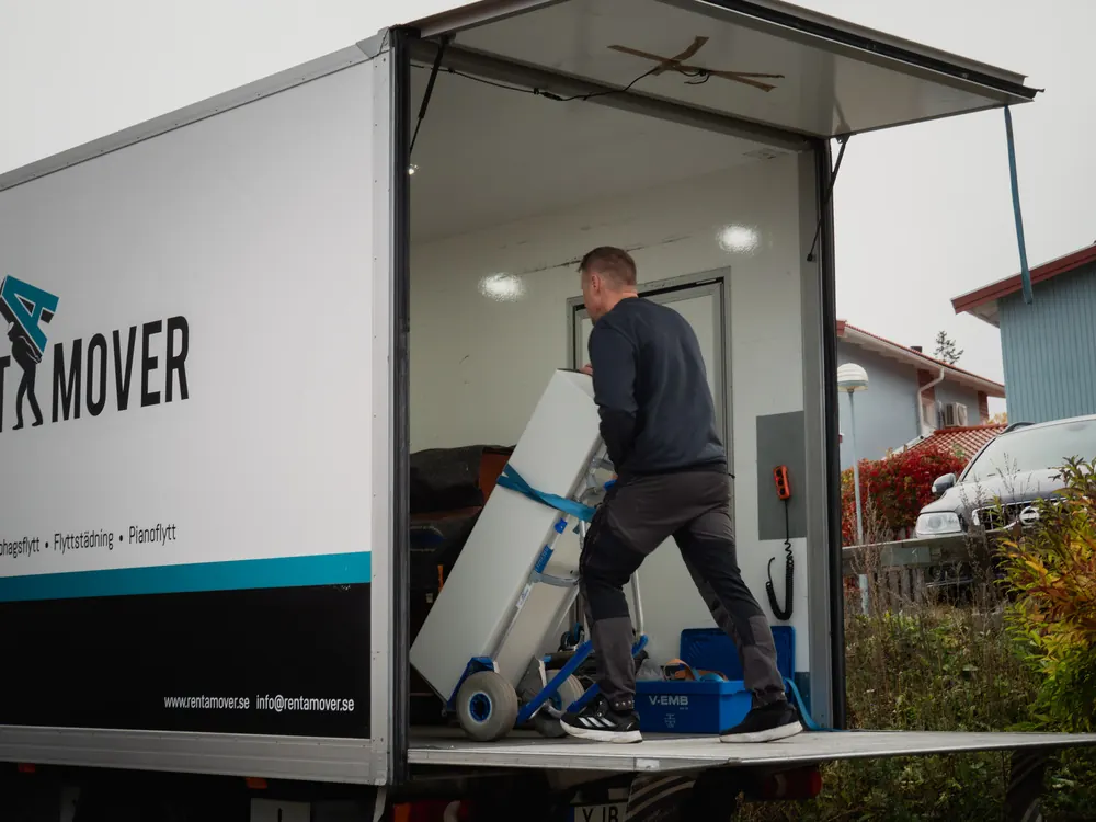Två flyttgubbar från Rent A Mover bär en tung soffa uppför en trappa vid bärhjälp för privatperson i Stockholm.
